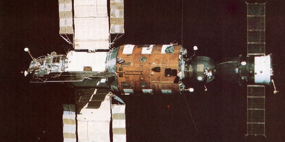 Het Saljoet 7 ruimtestation in een baan om de Aarde met een Sojoez ruimtecapsule er aan gekoppeld